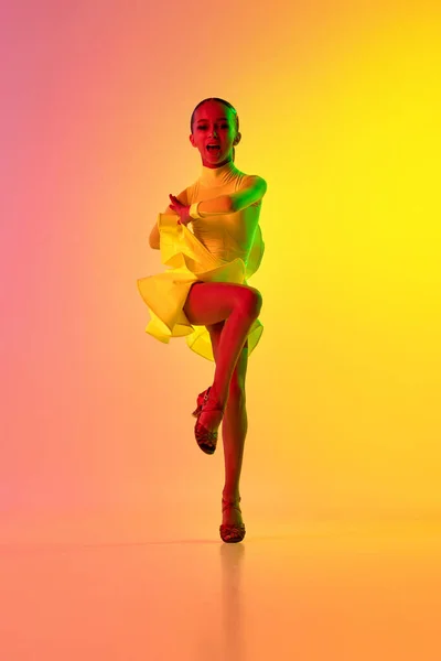 优雅的小女孩穿着可爱的舞台服 在霓虹灯滤光片的渐变粉色和黄色背景上跳舞 美的概念 专业的舞蹈 舞蹈中的情感 — 图库照片