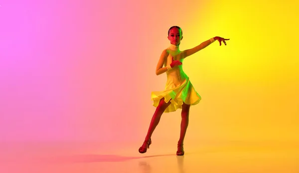 愛らしい舞台衣装を着たエレガントな女の子 ネオンライトフィルターでグラデーションピンク黄色の背景にダンスボールルームのダンスをドレスアップ 美しさ プロのダンス スキルの概念 ダンスにおける感情 — ストック写真