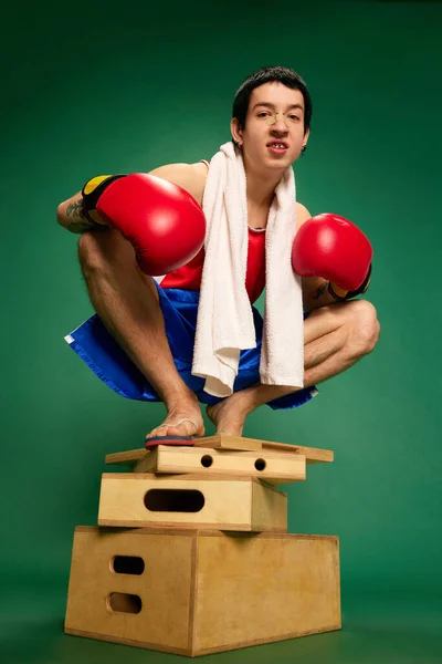 自信あり 緑の背景に隔離された木製の箱に座っているボクシングの手袋で若いボクサーの肖像画 スポーツ エネルギーの概念 — ストック写真