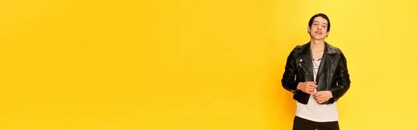 黄色の背景の上にカメラで笑みを浮かべて流行の革のジャケットで楽しい若い男とバナー ロックミュージシャン ファッション 学生生活 広告の概念 テキストのコピースペース — ストック写真