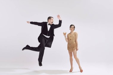 Dans eden çift. Retro adam ve klasik gece kıyafetleri içinde çekici bir kadın beyaz arka planda eğleniyorlar. Aşk ve müzik kavramı, cazibe ve moda, Amerikan kültürü.