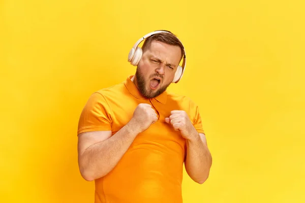 好きな曲を叫んで ヘッドフォンを装着したハンサムな男が音楽を聞いて黄色の背景に歌います 人間の感情 広告の概念 — ストック写真