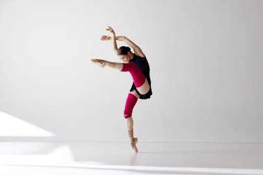 Zarafet gösteriyorum. Sivri uçlu ayakkabılar giyen genç ve güzel bir balerin dans ediyor ve beyaz arka plana bakıyor. Klasik bale kavramı, ilham, güzellik, dans, yaratıcılık