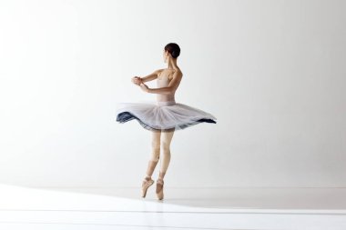 Beyaz arka planda izole bir şekilde dans eden güzel bir balerinin zarif hareketleri. Bale elbiseli kadın dansçı. Sanat, güzellik, arzu, yaratıcılık kavramı