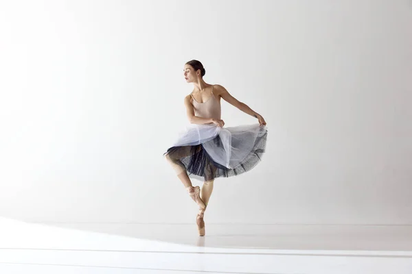 Aesthetic of classical dance. One adotable ballerina holding tutu and dancing over white background. Concept of classic ballet, inspiration, beauty, dance, creativity. Beauty of contemporary dance