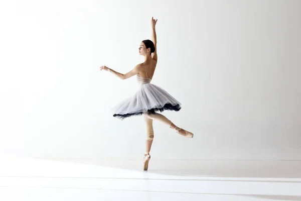 Showing flexibility and grace. Ballerina wearing tutu dancing elegant movements over white background. Beauty of classical dance. Concept of classic ballet, inspiration, beauty, dance, creativity