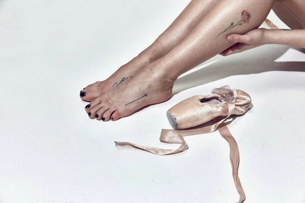 Exhausting hard work in dance hall. Cropped image of tired female legs, ballerina in pointe over white studio background. Concept of classic ballet, inspiration, beauty, dance, creativity