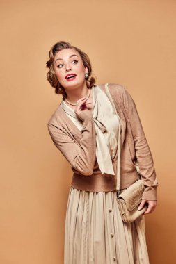 Meraklı bayan. Klasik kıyafetler giyen çekici bir kadın her şeye burnunu sokan bir yüz ifadesiyle bej arka plana bakıyor. İnsan duygularını, modasını, güzelliğini, eski tarzını, eski tarzını, 60 'lı yıllarını kavra