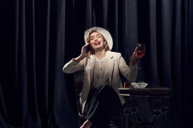 Heyecan verici bir konuşma. Kostümlü sevimli bir kadın telefonda parlak duygusal bir yüz ifadesiyle konuşuyor. Güzellik kavramı, moda, eski filmler, aktris, retro, vintage