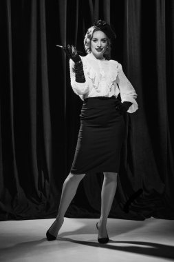 Kendine güvenen bir bayan. Zarif bir kostüm giymiş, sigara içen ve kameraya bakan çekici bir kadının portresi. Siyah beyaz fotoğraf. Güzellik kavramı, moda, eski filmler, aktris, retro, vintage