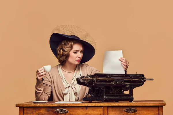 Confused. Attractive woman writer wearing old-fashioned clothes sitting at typewriter with surprised face. Concept human emotions, beauty, fashion, retro style, vintage, 60s, poems, novel