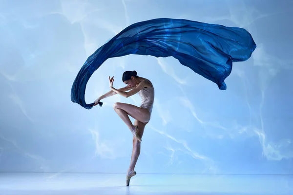 Flying fabric. Aesthetic of classical dance. One young ballerina wearing beige bodysuits emotional dancing with fabric silk. Concept of classic ballet, inspiration, beauty, dance, creativity