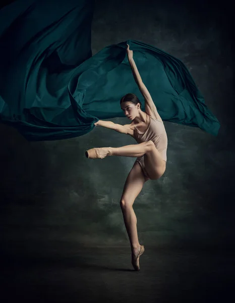 Solo performance. One emotional ballerina dancing with fabric on fingertips over dark green background. Aesthetic of ballet. The art, artist, movement, action and motion concept