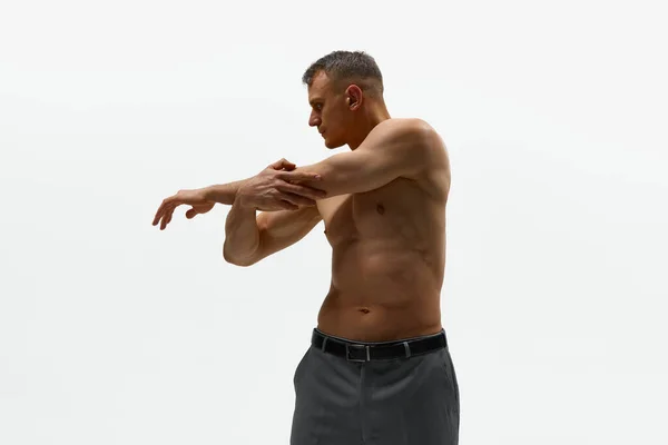 运动的身体在运动 他穿着裤子 赤身裸体站在镜头前 站在白色的背景上 被拍了下来 男性时尚 身体美学 男性健康的概念 — 图库照片
