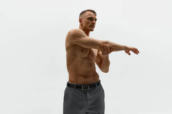 肌肉在运动 他穿着裤子 赤身裸体站在镜头前 站在白色的背景上 被拍了下来 男性时尚 身体美学 男性健康的概念 — 图库照片