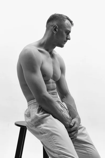 肌肉组织形态 赤身裸体 一个英俊而强壮的年轻人坐在椅子上摆姿势的画像 黑人和白人 男性健康 男性身体美丽的概念 — 图库照片
