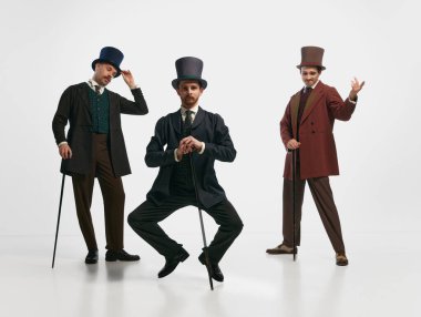 Beyler! Eski moda kıyafetler giyen ve beyaz arka planda poz veren üç adamın portresi. Tarihi yeniden yapılanma, çağların karşılaştırılması, retro, vintage, duygular, ruh hali, reklam