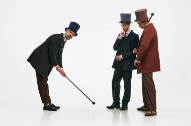 Eğlen biraz. Eski moda kıyafetler ve silindir şapkalar giyen beyaz arka planda eğlenen üç adamın portresi. Tarihi yeniden yapılanma kavramı, dönemin karşılaştırması, retro, vintage, duygu