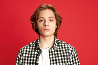 Üzgün, yorgun, bitkin. Kareli tişört giymiş genç bir çocuğun, duygusuz yüz ifadesiyle kameraya bakışının yakın portresi. İnsan duyguları kavramı, ruh hali, psikolojik durum, güzellik, reklam