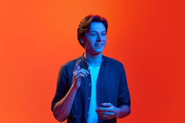 Fikir üreteci, başla. Genç bir adamın portresi, harika bir plan yapan öğrenci, kırmızı-turuncu arka plan üzerinden neon ışığı altında strateji. İş kavramı, gençlik, insani duygular, ruh hali, reklam