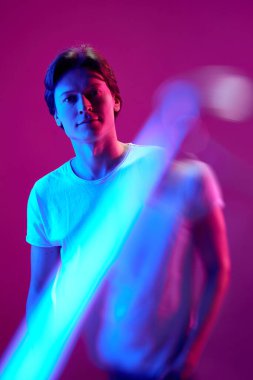 Rüya görmek, olumlu. Düşünceli genç bir adamın portresi, düşünceli bir yüzü olan ve pembe arka plandaki neon ışıkta kameraya bakan bir adam. Gençlik kavramı, insani duygular, yüz ifadesi, reklam