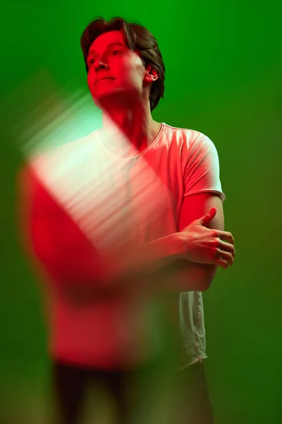 思慮深い 若い男の肖像画 男の思慮深い顔とネオンの光の中で緑の背景を見上げ立っている 若者の概念 人間の感情 — ストック写真
