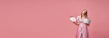 Hoşlanmamak. Üzgün, çekici, sarışın, pembe elbise giyen ve pembe stüdyo arka planında üzgün suratlı hediye kutusu tutan bir afiş. Ortaçağ, güzellik, doğum günü, insan duyguları kavramı.