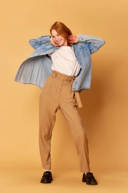 Mutluluk, neşe. Genç, pozitif, güzel bir kız, günlük kıyafetler giyen bir öğrenci kızıl arka planda kameraya poz veriyor ve gülümsüyor. Moda, güzellik, olumlu duygular, satış, reklam konsepti