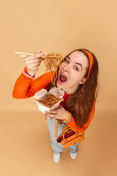 没有食物限制 与年轻貌美的学生的肖像 女孩拿着盒装食物和吃面条饥饿的脸姜汁工作室背景 广告的概念 — 图库照片
