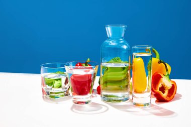 Sulu sebze salatası. Brokoli, kırmızı ve sarı biberli bir hayat mavi stüdyo arka planında bir şişe suyla. Sağlıklı gıda, diyet, beslenme, kilo kaybı, vitamin