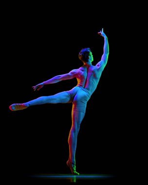 Zarif kaslı erkek balerin portresi. Karanlık stüdyo arka planında neon ışıkla dans ediyor. Zarafet, sanat, güzellik, modern dans konsepti. Arkadan bak. Ağırlıksız, esnek aktör.