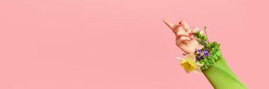 Bahar mevsimi modası. Pembe stüdyo arka planında, içinde güzel çiçekler olan kadın elinin yaratıcı portresi. Fotokopi alanı olan pankart. Şık kıyafetler, güzellik, sanat, yaratıcılık kavramı