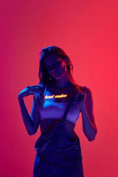 Video games world. Sexy cyberpunk girl with long hair and digital neon filter lights on body on red and pink background. Concept of digital art, video games, fashion, cyberpunk, futurism