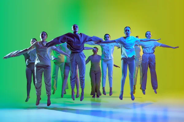 10代の若者のグループ 若いダンサーがネオンの光のグラデーションの背景に一緒に手を広げてジャンプします 現代のフリースタイルダンス 現代美術 創造的なライフスタイルの概念 — ストック写真