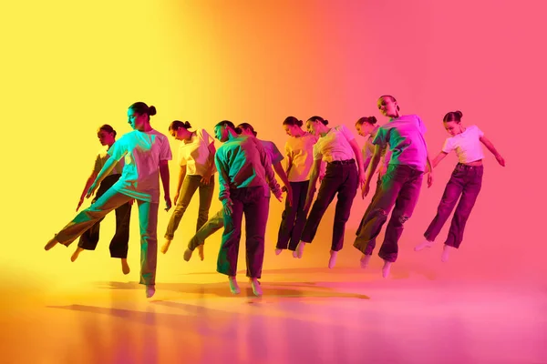 創造的な即興 10代の若者のグループは 若いダンサーが列に立って ネオンの光の中でピンクと黄色の背景にジャンプします 現代のフリースタイルダンス 現代美術 創造性の概念 — ストック写真