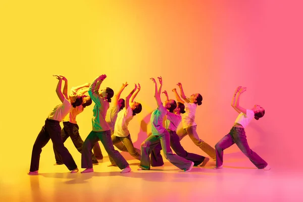 ダンストレーニングのプロセス 白いTシャツを着た美しい十代の女の子のグループは ジーンズはネオンの光の中でピンクと黄色のグラデーションの背景に一緒に踊ります モダンダンス コンテンポラリーアートのコンセプト — ストック写真