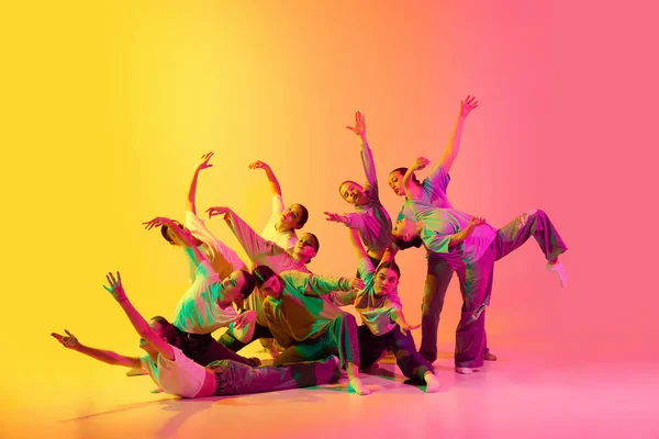 多様性 混乱と自由 若い人たちのグループは 女の子ネオンでピンクと黄色のグラデーションの背景に対してコンテンポラリーダンス 現代のフリースタイルダンス 現代美術 趣味の概念 — ストック写真