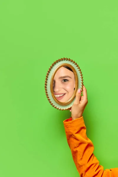 女性的手捧着一面镜子 倒映着美丽的女人的脸 有着天然的妆容 覆盖着明亮的绿色背景 创造力 人类情感 表达概念 — 图库照片