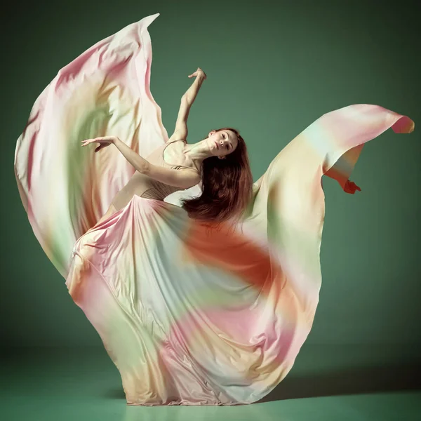 暗い緑のスタジオの背景の上にダンスで回転絹のドレスを身に着けている1人の若い女の子 豪華なバレリーナと肖像画 古典バレエ インスピレーション 美しさ ダンス 創造性 芸術の概念 — ストック写真
