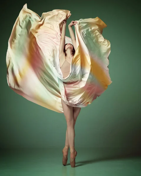 柔軟性と優雅さを示す カラフルなドレスを身に着けているバレリーナは ダークグリーンのスタジオの背景にファブリックでエレガントな動きを踊る 古典バレエ インスピレーション 美しさ 創造性の概念 — ストック写真