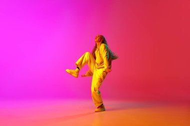 Komik dans. Moda kıyafetleri giymiş modern genç dansçıların portresi neon ışıklarıyla değişen pembe arka planda. Çağdaş dans tarzı, hareket, sanat, hareket, gençlik kültürü, reklam kavramı