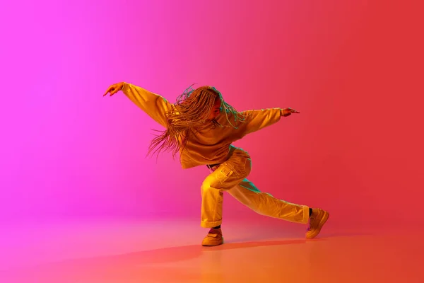 霹雳舞一个年轻姑娘的画像 一个带着辫子的舞者 带着激情在霓虹灯下的渐变粉红背景上跳舞 当代舞蹈风格 灵感概念 — 图库照片