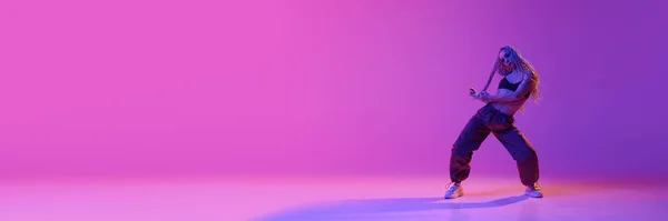 自由泳 横幅与迷人的年轻女子 女孩与辫子在霓虹灯下欢快地跳着独舞 背景是紫色的 当代舞蹈 业余爱好的概念 — 图库照片