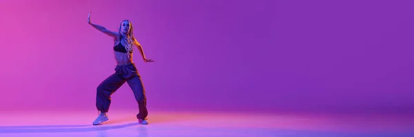 ネオンの光の中でグラデーション紫色の背景に異常な動きを踊る若い愛らしい女の子と肖像画 バナーだ コンテンポラリーダンスのスタイル アート インスピレーション 広告の概念 — ストック写真