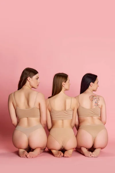 女性身体的美丽 与一群年轻女孩的肖像 穿着米色内装的女人坐在粉红色的工作室背景上 皮肤护理 健康饮食 整形手术 化妆品 广告等概念 — 图库照片