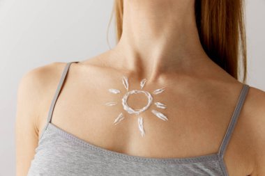 Güneş koruması kozmetik. Beyaz renkli stüdyo arka planında güneş kremi sürmüş, iç çamaşırlı, ince kadın vücudunun kesilmiş görüntüsünü kapat. Vücut bakımı, sağlık, spf, tatil, yaz, güneş reklamı kavramı