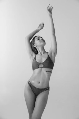 Genç, gülümseyen bir kızın portresi, beyaz renkli stüdyo arka planında güneş kremi kullanan mayolu bir kadın. Tek renkli olsun. Sağlık kavramı, spf, tatil, yaz, güneş kremi, güneş kremi, reklam