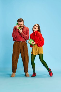 Beyin testeresi. Evli bir çiftin portresi, retro kıyafetler giyen bir adam ve gülümseyen bir kadın mavi stüdyo arka planında kameraya bakıyor. Aile kavramı, ilişki, aşk, duygular, retro, çatışma