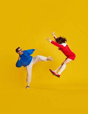 Komik bir çiftin portresi, oyuncu kadın ve erkek sarı stüdyo arka planı için sahnede kavga ediyorlar. Aile kavramı, ilişki, aşk, insan duyguları, retro, çatışma, sanat, tiyatro, reklam