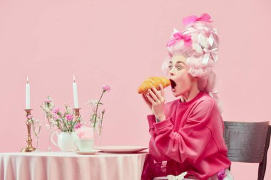 Portrait with surprised princess, queen wearing big wig and starting eat huge croissant on pink background with astonished face. Concept of food, diet, comparison of eras, modernity and renaissance clipart